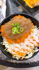 Japanese chicken katsu rice bowl with crispy breaded cutlet, shredded cabbage, fresh carrots, mayonnaise drizzle, savory sauce topping, and green onion garnish, authentic Asian donburi mea
