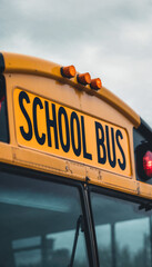 Close-up of yellow school bus roof with &ldquo;SCHOOL BUS&rdquo; lettering and lights