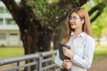 Asian female student in warm clothes using phone to chat with friends and ready for video call while in university.