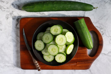 Cucumber sliced in a black color plate on top view. Healthy eating and diet food.