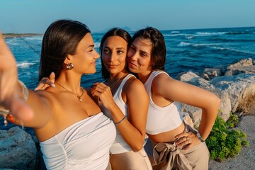 Three women taking selfie by the sea