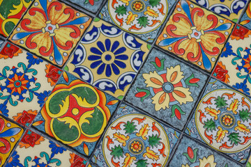 Closeup of a colorful pattern of traditional Spanish or Portuguese ceramic tiles, each adorned with unique, hand-painted floral and geometric designs