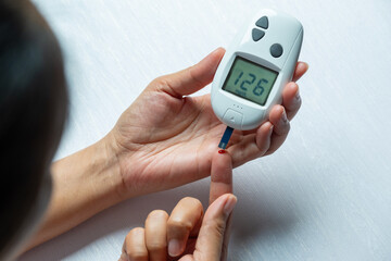 hand of people check diabetes and high blood glucose monitor with digital pressure gauge. Healthcare and Medical concept	