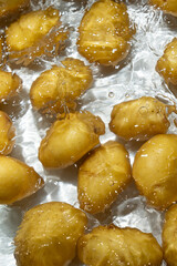 Whole Organic Raw Potatoes In Water Top View, Splash And Ripples.