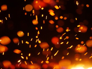 The image is a close up of a fire with lots of sparks flying out of it