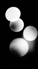 Abstract Four blurred circles in shades of gray on a black background, varying in clarity and opacity, creating depth
