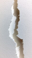 Delicate Tear in Textured White Paper Revealing Smooth Backdrop with Subtle Depth
