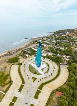 Aerial view of the shimmering, blue-toned monument rising gracefully from the circular plaza where the ocean meets the shore, Puerto Colombia, Atlantico, Colombia.