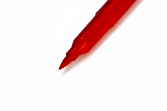 Close-up of a red marker tip. The tip is a pointed, fine-tipped design, with a shiny red plastic body