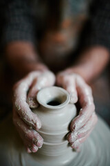 Caucasian middle aged man shaping clay vase on pottery wheel, hands covered in wet clay, focusing on precise molding technique, close up of creative process in studio