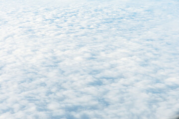 Aerial view of a vast expanse of puffy, white clouds resembling a sea. The soft, ethereal quality of the clouds creates a dreamlike atmosphere