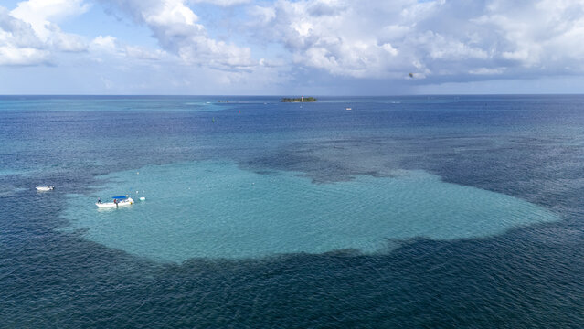 Aerial view of the vibrant turquoise waters meet the deeper blues, with boats gently floating near the coral reefs, Haynes Cay island afar, San Andr&Atilde;&copy;s, San Andres and Providencia, Colombia.