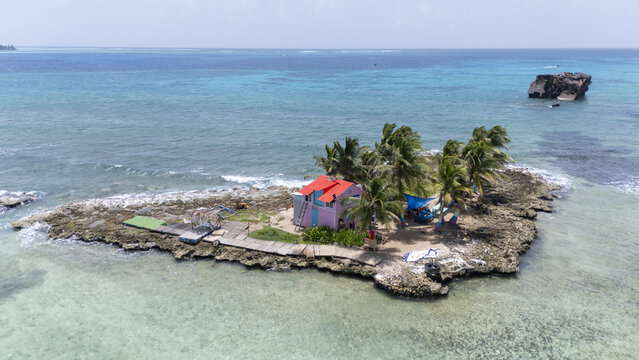 Aerial view of a small island featuring a pink house with a red roof surrounded by azure waters, San Andr&Atilde;&copy;s, San Andres and Providencia, Colombia.