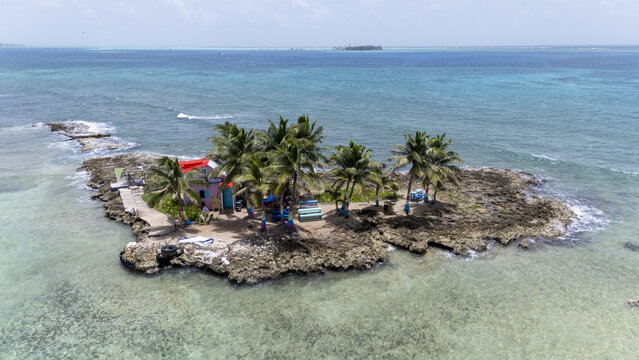 Aerial view of a tiny island with palm trees, a colorful building, and turquoise waters shimmering under the bright sun, San Andr&Atilde;&copy;s, San Andres and Providencia, Colombia.