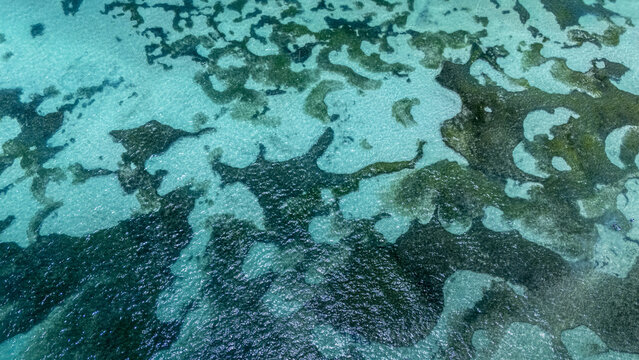 Aerial view of turquoise waters blending with dark rocky formations beneath the surface, creating a mesmerizing contrast of color and texture, San Andr&Atilde;&copy;s, San Andres and Providencia, Colombia.