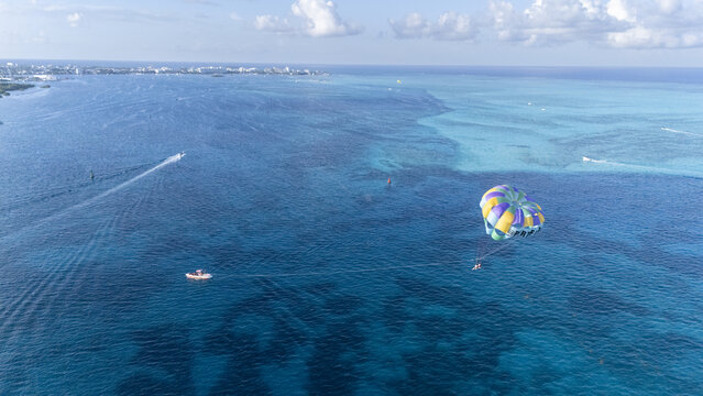 Aerial view of a vibrant parasail drifting over the turquoise and azure waters, with boats leaving white wakes towards the distant shoreline, San Andr&Atilde;&copy;s, San Andres and Providencia, Colombia.