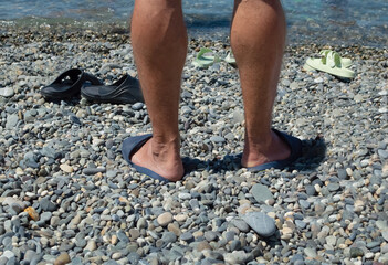 Close-up of a man's legs on a pebble beach