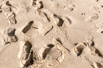 Various footprints mark a sandy beach, depicting a human presence and the ephemeral nature of seaside experiences