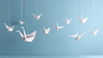Origami cranes hanging from strings against a light blue backdrop