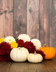 Autumnal arrangement of flowers and pumpkins on a wooden surface