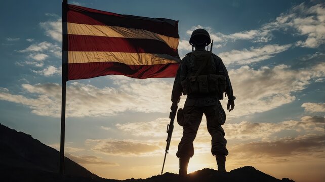 Silhouette of a soldier standing in front of the american flag at sunset