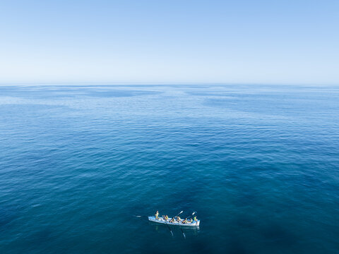 Aerial view of a rowing boat gliding across the glassy, turquoise waters under a clear sky, the epitome of serenity., Perth, Western Australia, Australia.