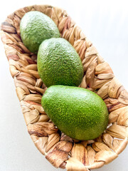 Fresh Green Avocados in Woven Natural Basket on White