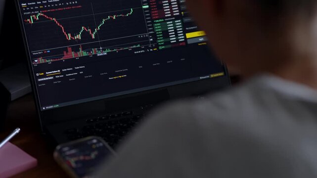 Focused trader analyzing cryptocurrency charts on laptop and smartphone

