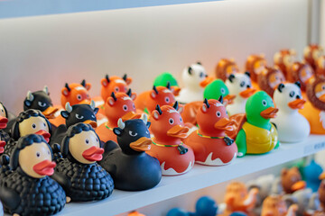 Shelves filled with unusual rubber ducks, focus on rubber duck cow, foreground and background blurred