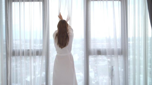 A young woman in red lingerie wakes up from a rest and relaxes by the window, healthy lifestyle and morning routine