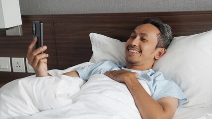 man making video call in bed