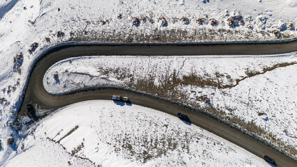Aerial view of snow-covered mountain road with vehicles on a winter day