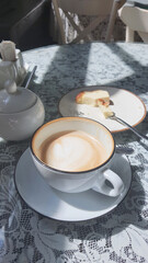 Coffee and cake served on a lace-covered table in a cozy cafe setting