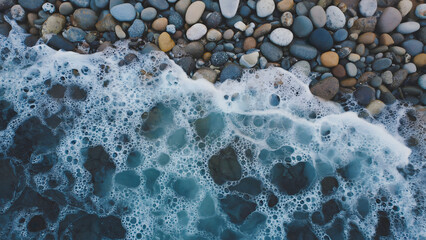 Soothing aerial perspective of sea waves crashing on a tranquil stony shore