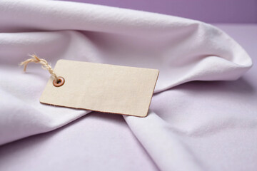 Close-up of minimalist woven fabric tag on soft blue linen cloth for branding mockup, fashion packaging, identity label, or minimalist textile product design presentation with copy space