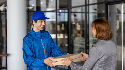 Obraz premium Senior or elderly manager receives a parcel from a delivery man in front of the office building.