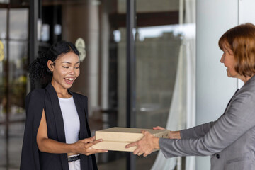 Young African office worker receives a surprise gift from her supervisor. Young lady feels very happy when getting a token of appreciation or award from her boss in front of the office. Outstanding