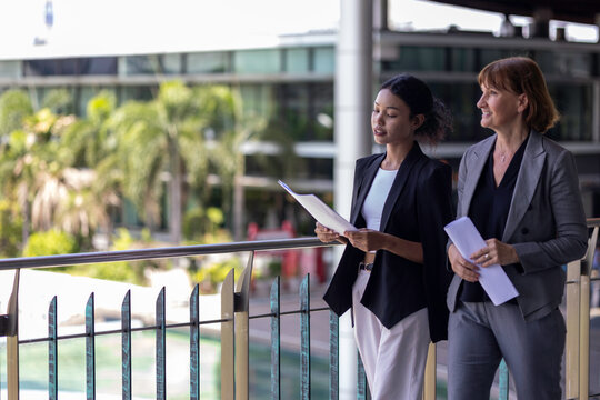 Conversation between a female senior manager with her young African coworker using data and diagram to design for a business development plan. Working across generations and cultures