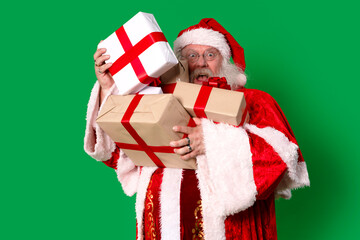 Santa Claus happily holds festive presents on a bright green background during the Christmas season, ready to spread joy and cheer to children everywhere