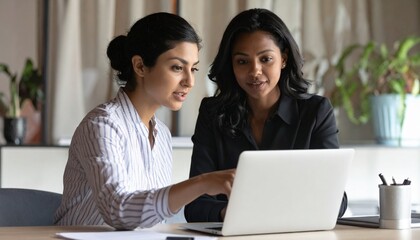 Close up confident Indian businesswoman mentor teaching African American intern. Using laptop, pointing at computer screen. Helping with corporate software. Detailed high quality image.