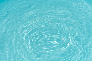 Blue water with ripples on the surface. Defocus blurred transparent blue colored clear calm water surface texture with splashes and bubbles. Water waves with shining pattern texture background.