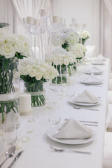 Long wedding banquet table with elegant white floral arrangements.