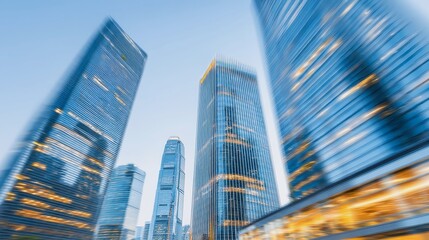 Fototapeta premium A city skyline with tall buildings and a blue sky. The buildings are lit up at night, creating a bright and lively atmosphere