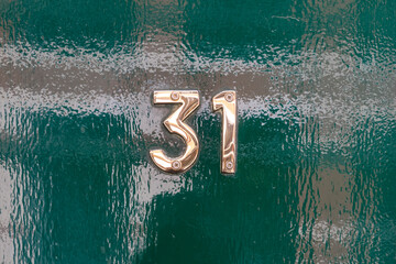 Brass number thirty one on glossy green door
