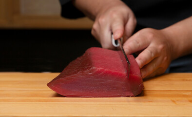 Chef slicing raw tuna fillet for sushi