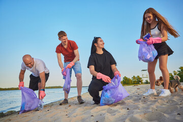 Parents and kids cleaning beach together with gloves and eco bags. Concept of family teamwork, eco responsibility, sustainability, unity, and positive lifestyle.