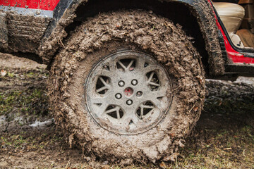 Close up photo of a MT mud terrain tires muddy dirty texture under 1996 red modified, lifted, stock old 4x4  off-road American SUV vehicle   