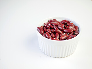 Red bean seeds in a white bowl on a white background