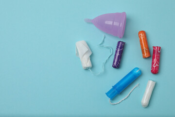 feminine pads, tampons, menstrual cup feminine hygiene products on a blue background
