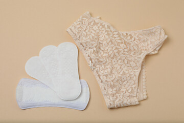 feminine pads, tampons, menstrual cup feminine hygiene products on a beige background
